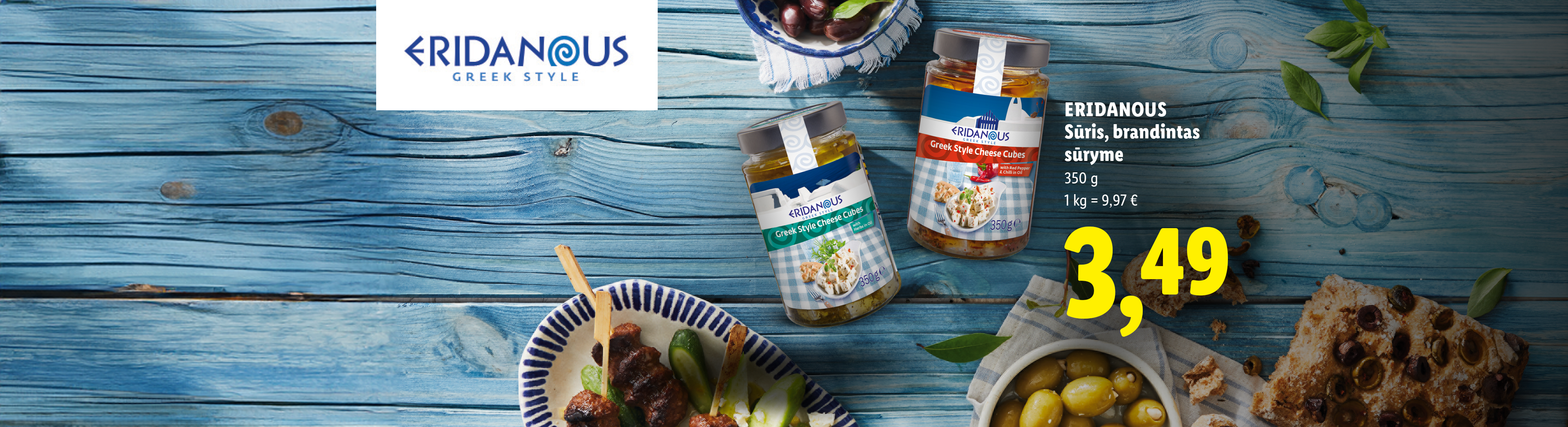 Graikiško stiliaus sūrio kubeliai aliejuje, patiekiami su alyvuogėmis ir duona, ant mėlyno medinio paviršiaus.